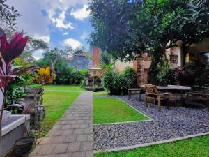 un jardín con un banco y una mesa en Sahadewa House, en Ubud