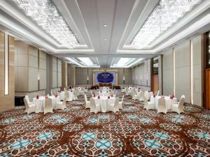 un salón de banquetes con mesas blancas y sillas blancas en Aston Solo Hotel, en Solo