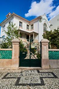 een wit huis met een zwarte poort ervoor bij Vila Branca Guesthouse - Palacete in Figueira da Foz