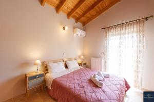 a bedroom with a bed with a pink bedspread and a window at Villa Pine Forest in Corfu Town