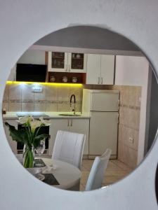 uma cozinha com armários brancos e uma mesa e cadeiras em Harmony cozy home em Podgorica