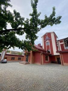 un edificio rosso con un albero di fronte di T&S Apart-Hotel a Černivci