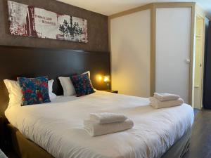 een slaapkamer met een groot bed en handdoeken bij SHELDER Hôtel - CHERBOURG EN COTENTIN - Equeurdreville in Cherbourg en Cotentin