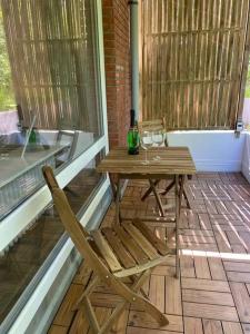 una mesa de madera y una silla en un porche con una botella de vino en Central Apartment Flensburg, en Flensburg