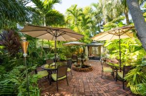 un patio avec des tables, des chaises et des parasols dans l'établissement The Mermaid & The Alligator, à Key West