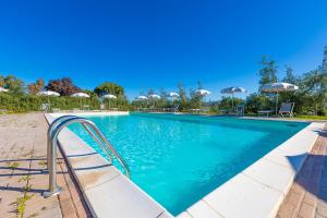 una piscina con acqua blu e ombrelloni di Agriturismo Gli Etruschi a Populonia