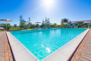 una piscina con acqua blu e ombrelloni di Agriturismo Gli Etruschi a Populonia