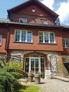 a large wooden house with windows and plants at Willa Skalniak in Lądek-Zdrój