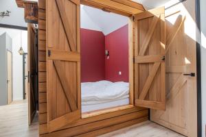 Cette petite chambre comprend un lit à l'intérieur d'une porte en bois. dans l'établissement erve Middendorp, à Ansen