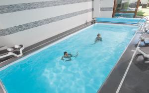 2 personas nadando en una piscina en Nicey - Hôtel Spa, Lounge, Coworking, en Romilly-sur-Seine