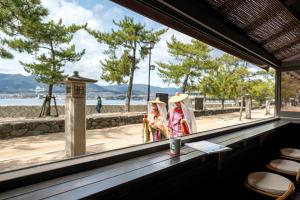 zwei Personen in Kostümen, die vor einem Fenster stehen in der Unterkunft Kinsuikan in Miyajima