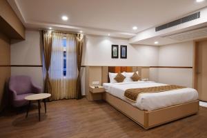 een hotelkamer met een bed en een stoel bij Soho Boutique Hotel in Mysore