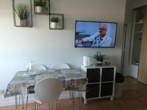 ein Wohnzimmer mit einem Tisch und einem TV an der Wand in der Unterkunft Casa ao Mar in Monte Gordo