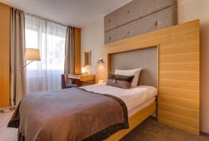 Schlafzimmer mit einem großen Bett mit einem Kopfteil aus Holz in der Unterkunft Continental Hotel Lausanne in Lausanne