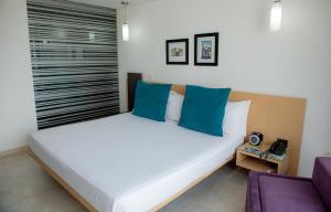 1 dormitorio con 1 cama blanca grande con almohadas azules en Hotel CasaBlanca Cucuta, en Cúcuta