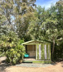 uma pequena casa verde com um alpendre e árvores em Camping la Clé des Champs em Calvi