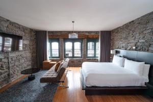 um quarto com uma cama e uma parede de pedra em Le Petit Hôtel Vieux-Montréal - Saint-Paul by Gray Collection em Montréal