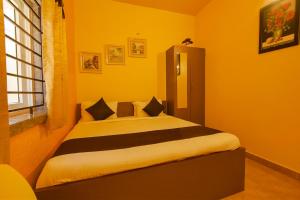 Un dormitorio con una cama con paredes amarillas y una ventana en FabHotel Vijaylakshmi Stay Inn - Nr Meenambakkam Metro Station, en Chennai