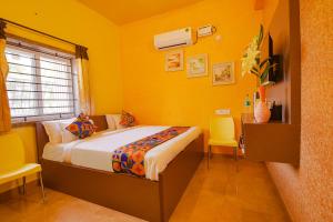 1 dormitorio con paredes amarillas, 1 cama y sillas en FabHotel Vijaylakshmi Stay Inn - Nr Meenambakkam Metro Station, en Chennai