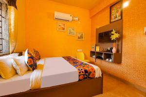 1 dormitorio con cama y pared amarilla en FabHotel Vijaylakshmi Stay Inn - Nr Meenambakkam Metro Station, en Chennai