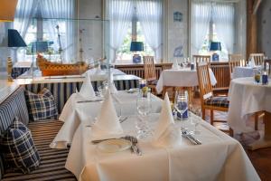 un comedor con mesas y sillas blancas en Hotel und Restaurant Jörg Müller, en Westerland