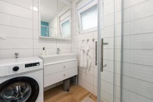 bagno bianco con lavatrice e lavandino di Apartmani Diva a Zara (Zadar)