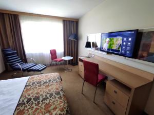 um quarto de hotel com um quarto com uma televisão numa secretária em Hotel HP Park Poznań Malta em Poznań