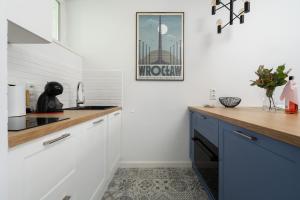 una cucina con pareti bianche e armadi blu di Old Town Studio by Noclegi Renters a Breslavia