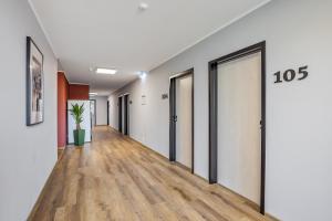 - un couloir avec des murs blancs, du parquet et des portes dans l'établissement Hostel Am Windberg, à Freital