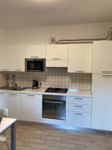 a kitchen with white cabinets and a stove top oven at Casa Lisa in Lenno