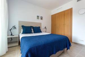 a bedroom with a blue bed with a wooden cabinet at NIDO 150 Mestral in Roses