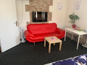 un sofá rojo en una habitación con chimenea en ZLATÁ-ÉRA, en Ostrava