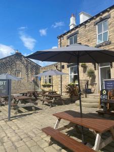 a group of picnic tables with an umbrella at The White Swan, Yeadon in Yeadon