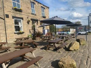 a group of wooden benches and an umbrella in front of a building at The White Swan, Yeadon in Yeadon