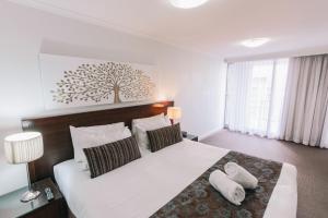 a bedroom with a large white bed with two pillows at Newcastle Central Plaza Apartment Hotel Official in Newcastle