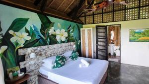 ein Schlafzimmer mit einem Bett mit einem Blumenbild in der Unterkunft Fox & The Firefly Cottages in Loboc