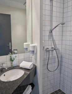 La salle de bains est pourvue d'un lavabo et d'une douche. dans l'établissement Huset Middelfart, à Middelfart