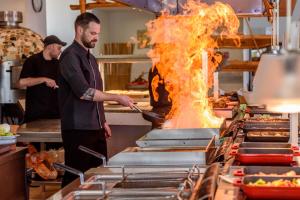 um homem a cozinhar comida numa cozinha com fogo em Star Beach Village & Water Park em Hersonissos