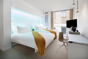 um quarto de hotel com uma grande cama branca e uma secretária em St Martins Lane London em Londres