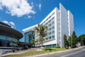 un edificio blanco con una palmera delante en Lagoas Park Hotel, en Oeiras