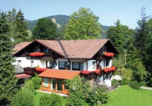 ein großes weißes Haus mit roten Blumen drauf in der Unterkunft Alpenlodge Pfronten in Pfronten