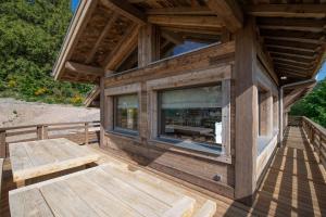 a wooden cabin with a large window on a deck at Aigle des Neiges 5 étoiles in Gérardmer