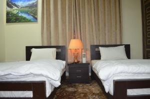 a bedroom with two beds and a lamp on a night stand at Hotel Astro in Gilgit