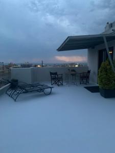 een balkon met stoelen en tafels op een dak bij Stylish Seaview Rooftop in Thessaloniki