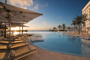 a resort swimming pool with lounge chairs and the ocean at Le Blanc Spa Resort Cancun - Adults Only - All-Inclusive in Cancún