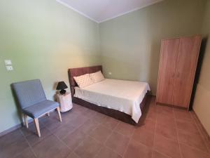 1 dormitorio con 1 cama, 1 silla y 1 armario en Lotaki the friendly house, en Limenaria