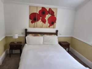 a bedroom with a bed with red flowers on the wall at Woodlands Lodge Hotel in Bartley