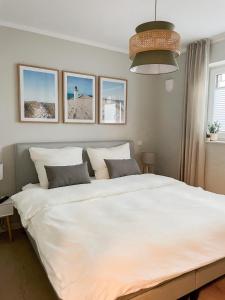 una camera da letto con un grande letto bianco con quattro immagini sul muro di Ferienwohnung Swedish Summer a Scharbeutz