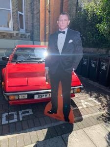 Un uomo in smoking accanto a un'auto rossa di Southsea Royale James Bond 3 bed Cool Penthouse, seafront parking a Portsmouth