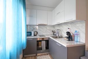 eine Küche mit weißen Schränken und einem blauen Vorhang in der Unterkunft Verona Apartment in Sandanski